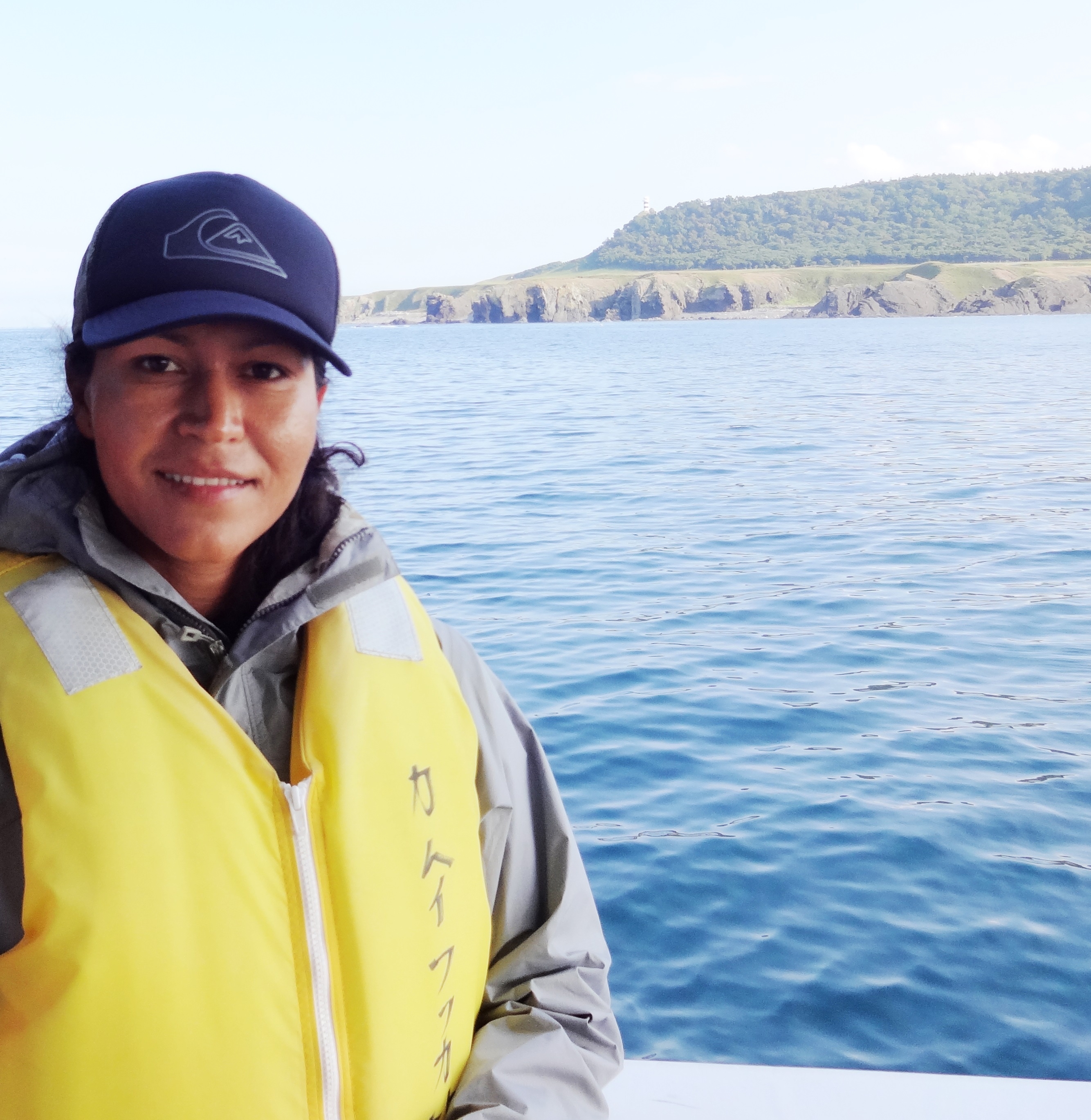 Mary in a yellow life vest overlooking the ocean.